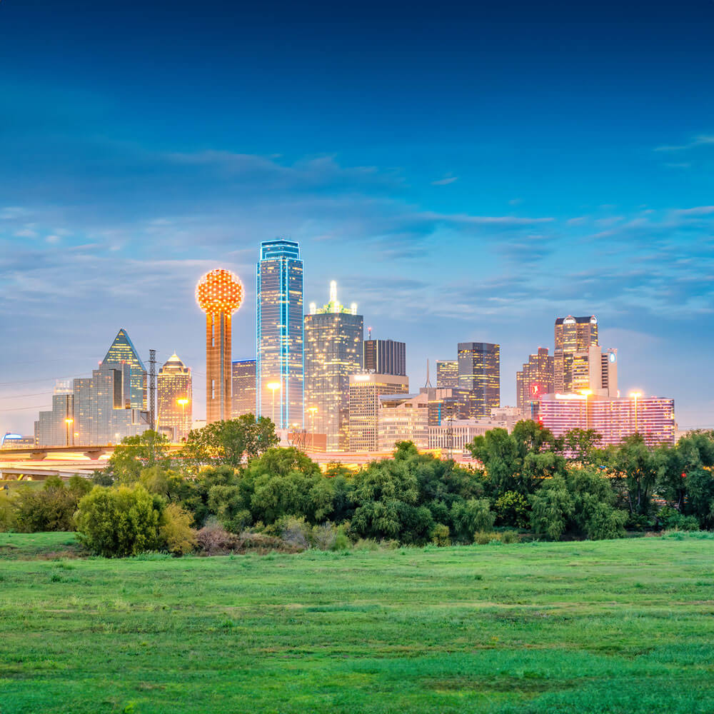 The Dallas skyline glows with colorful lights at twilight, showcasing the city’s modern architecture and vibrant atmosphere.