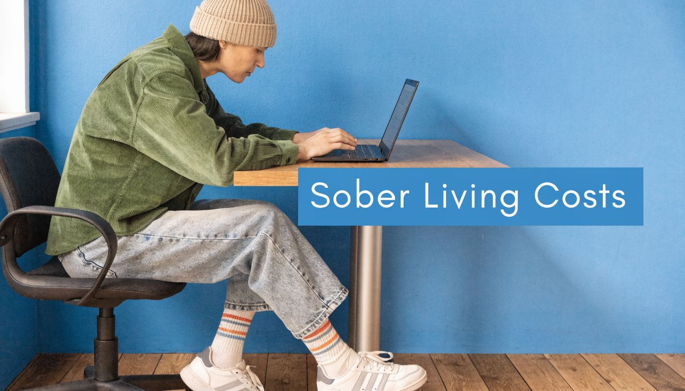 A person wearing a beanie and corduroy shirt working on a laptop at a table.