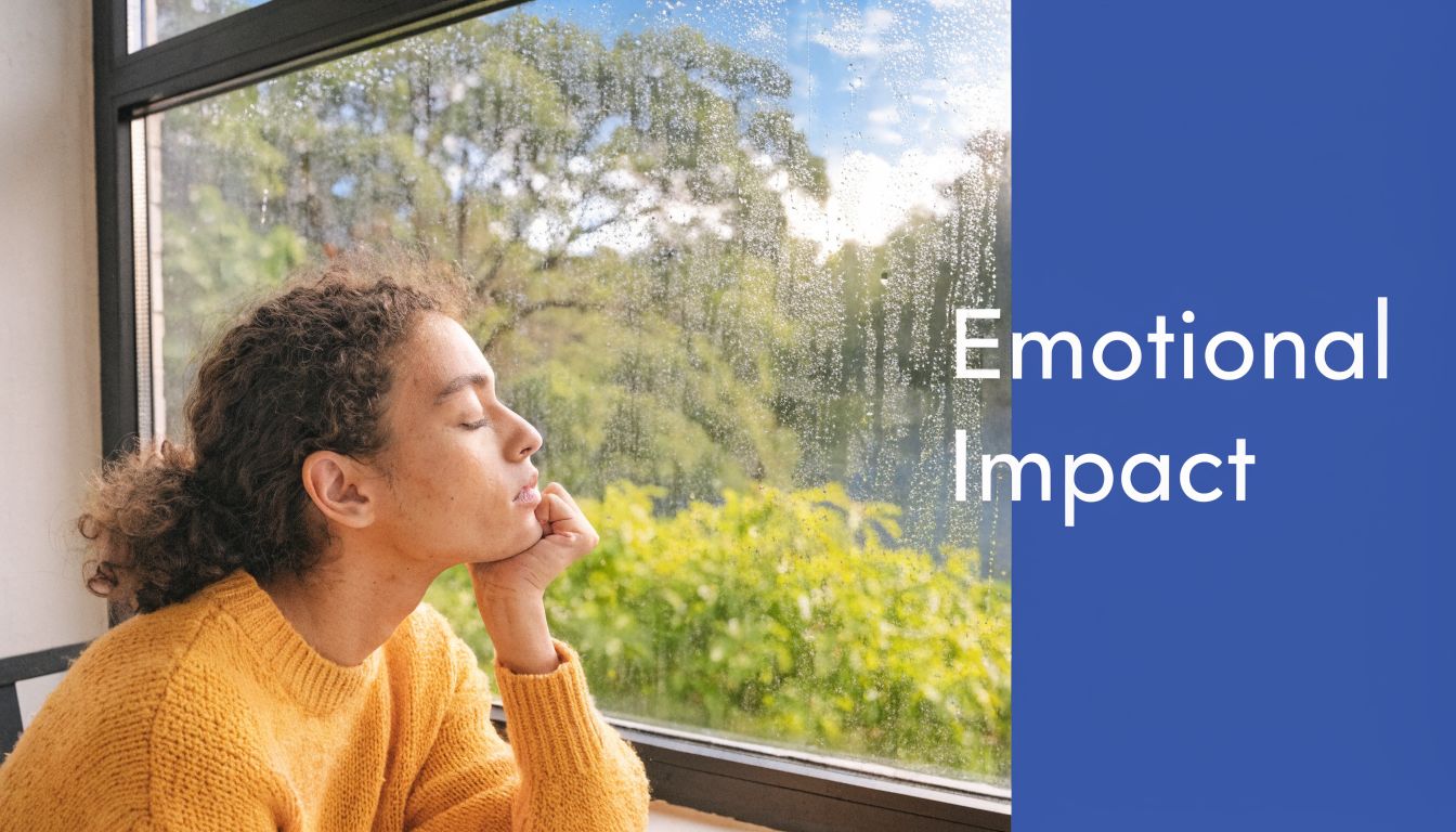 A person with curly hair wearing a yellow sweater looking out a rain-streaked window feeling emotional.