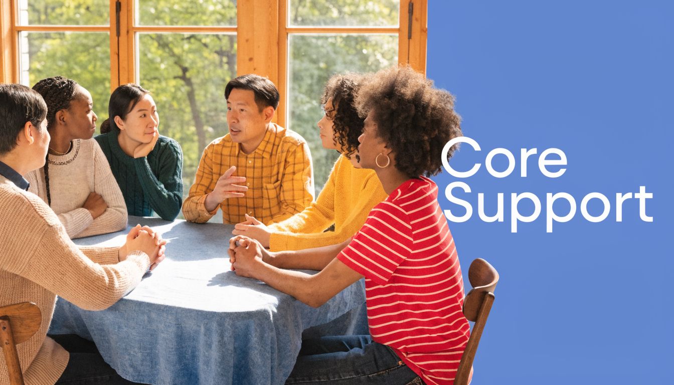 A diverse group of people sitting around a table having a supportive group therapy discussion together.