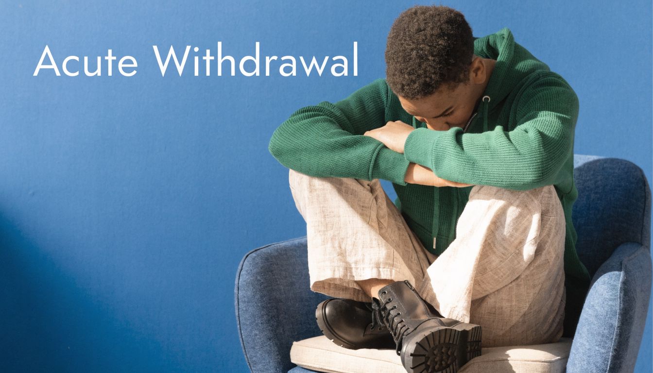 A young person sits curled up in a chair looking distressed, representing the struggle of acute withdrawal.