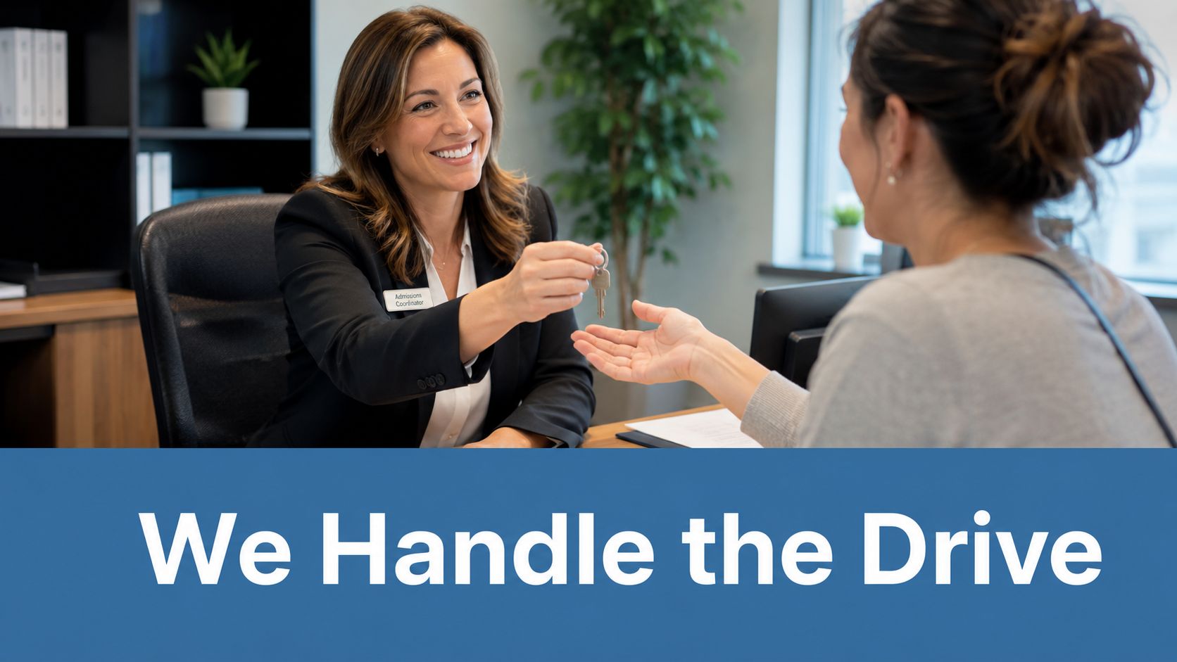 A professional admissions coordinator smiling while handing a set of house keys to a client.
